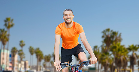 Image showing happy young man riding bicycle over venice beach