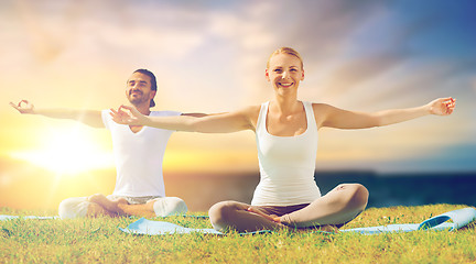 Image showing happy couple making yoga and meditating outdoors