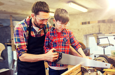 Image showing father and son with saw working at workshop