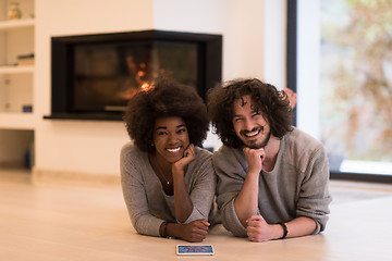 Image showing multiethnic couple lying on the floor  in front of fireplace