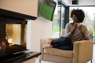 Image showing black woman drinking coffee in front of fireplace