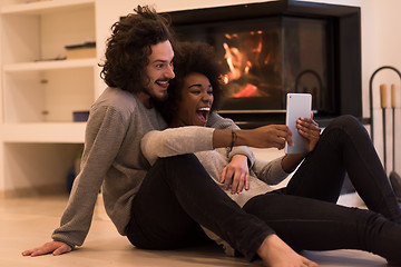 Image showing multiethnic couple using tablet computer on the floor