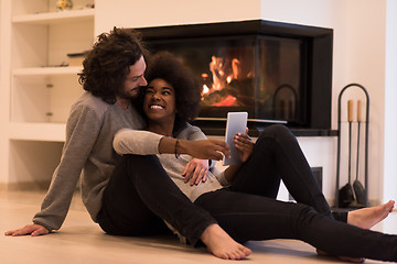 Image showing multiethnic couple using tablet computer on the floor