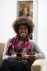 Image showing black woman sitting on sofa and using mobile phone
