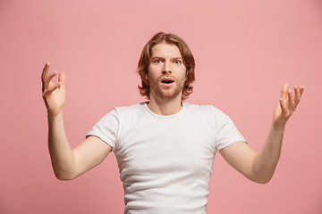 Image showing The young attractive man looking suprised isolated on pink