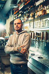 Image showing Barman in a pub near beer taps