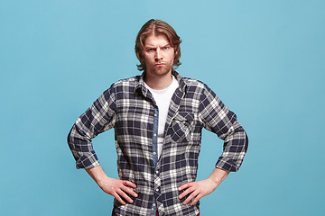 Image showing The serious business man standing and looking at camera against bllue background.