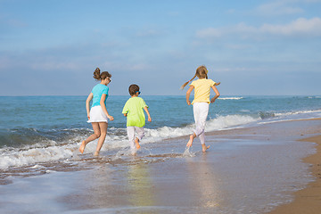 Image showing Three happy children running on the beach at the day time.