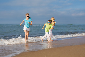 Image showing Three happy children running on the beach at the day time.