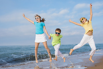 Image showing Three happy children running on the beach at the day time.