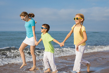 Image showing Three happy children running on the beach at the day time.