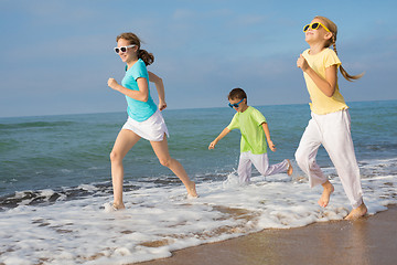 Image showing Three happy children running on the beach at the day time.