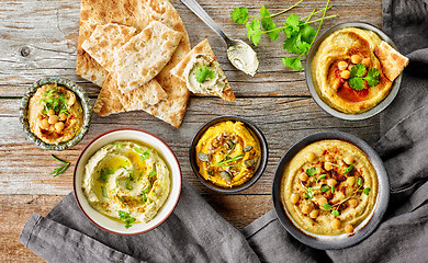 Image showing various hummus spreads on wooden table