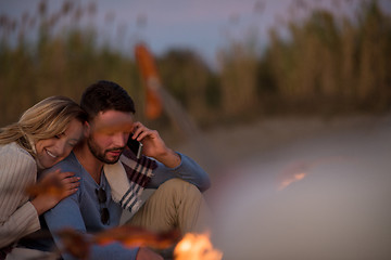 Image showing Group Of Young Friends Sitting By The Fire at beach