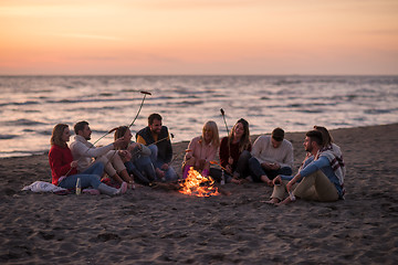 Image showing Group Of Young Friends Sitting By The Fire at beach