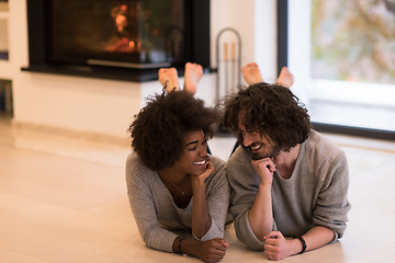 Image showing multiethnic couple lying on the floor  in front of fireplace