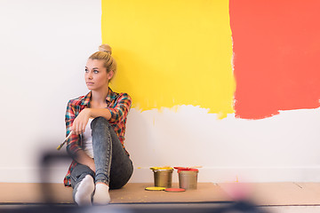 Image showing young female painter sitting on floor