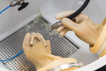 Image showing Dental Technician Cleans 3D Printed Dental Implant Bridge