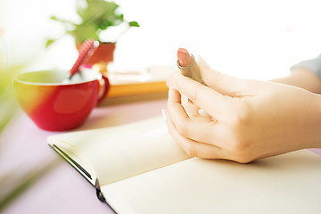 Image showing The female hands holding pomade. The trendy pink desk.