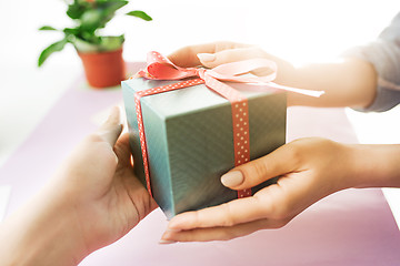 Image showing Close-up of female hands holding a present. The trendy pink desk.