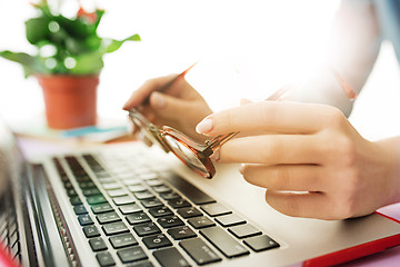 Image showing Woman working on computer in office and holding glasses