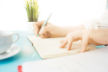 Image showing The male hands holding pen. The trendy blue desk.