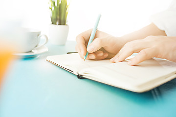 Image showing The male hands holding pen. The trendy blue desk.