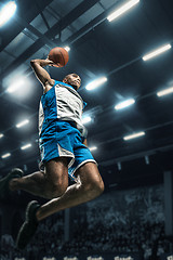 Image showing Basketball player on big professional arena during the game. Basketball player making slam dunk.