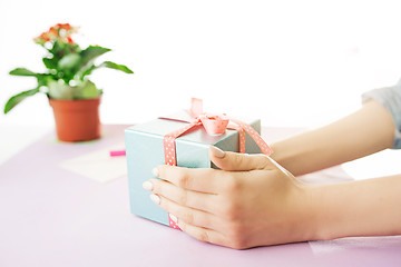 Image showing Close-up of female hands holding a present. The trendy pink desk.