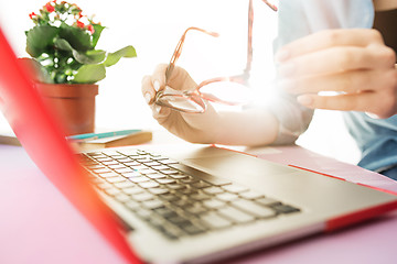 Image showing Woman working on computer in office and holding glasses