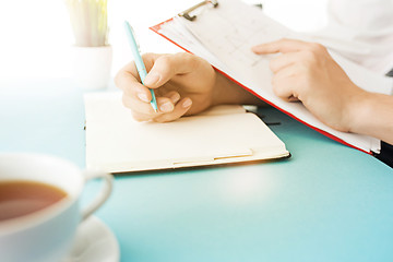 Image showing The male hands holding pen. The trendy blue desk.