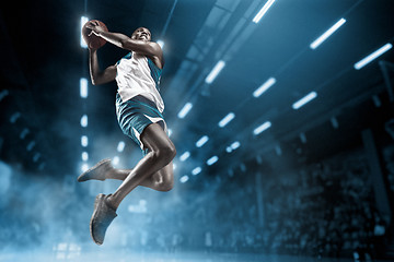Image showing Basketball player on big professional arena during the game. Basketball player making slam dunk.