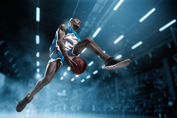 Image showing Basketball player on big professional arena during the game. Basketball player making slam dunk.