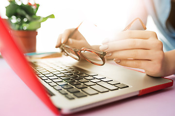 Image showing Woman working on computer in office and holding glasses