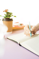 Image showing The female hands holding pen. The trendy pink desk.