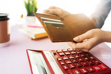 Image showing woman is holding purse, credit card in hands and calculating the costs