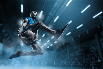 Image showing Basketball player on big professional arena during the game. Basketball player making slam dunk.