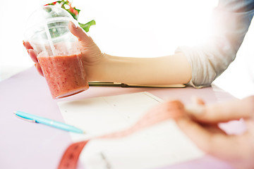 Image showing centimeter, pen, dieting and people concept - close up of woman hands with fruits and fresh juice sitting at table