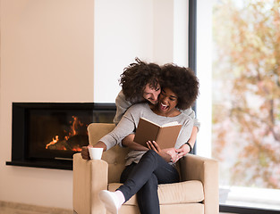 Image showing multiethnic couple hugging in front of fireplace