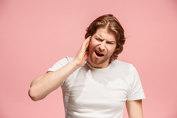 Image showing The Ear ache. The sad man with headache or pain on a pink studio background.