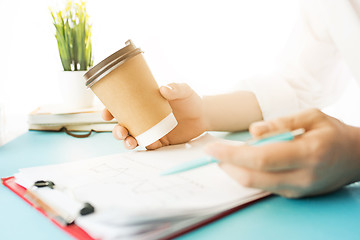 Image showing The male hands holding pen and coffee. The trendy blue desk.