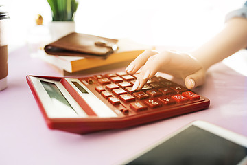 Image showing woman is holding purse, credit card in hands and calculating the costs