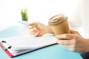 Image showing The male hands holding pen and coffee. The trendy blue desk.