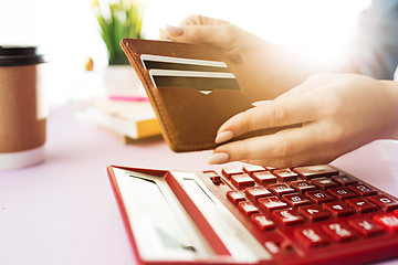 Image showing woman is holding purse, credit card in hands and calculating the costs