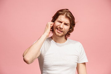 Image showing The Ear ache. The sad man with headache or pain on a pink studio background.