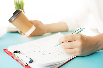 Image showing The male hands holding pen and coffee. The trendy blue desk.