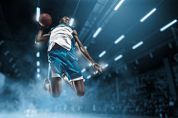 Image showing Basketball player on big professional arena during the game. Basketball player making slam dunk.