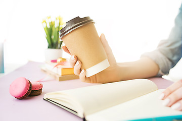 Image showing The female hands holding coffee. The trendy pink desk.
