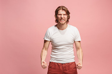 Image showing The young emotional angry man screaming on pink studio background