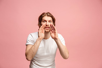 Image showing Isolated on pink young casual man shouting at studio